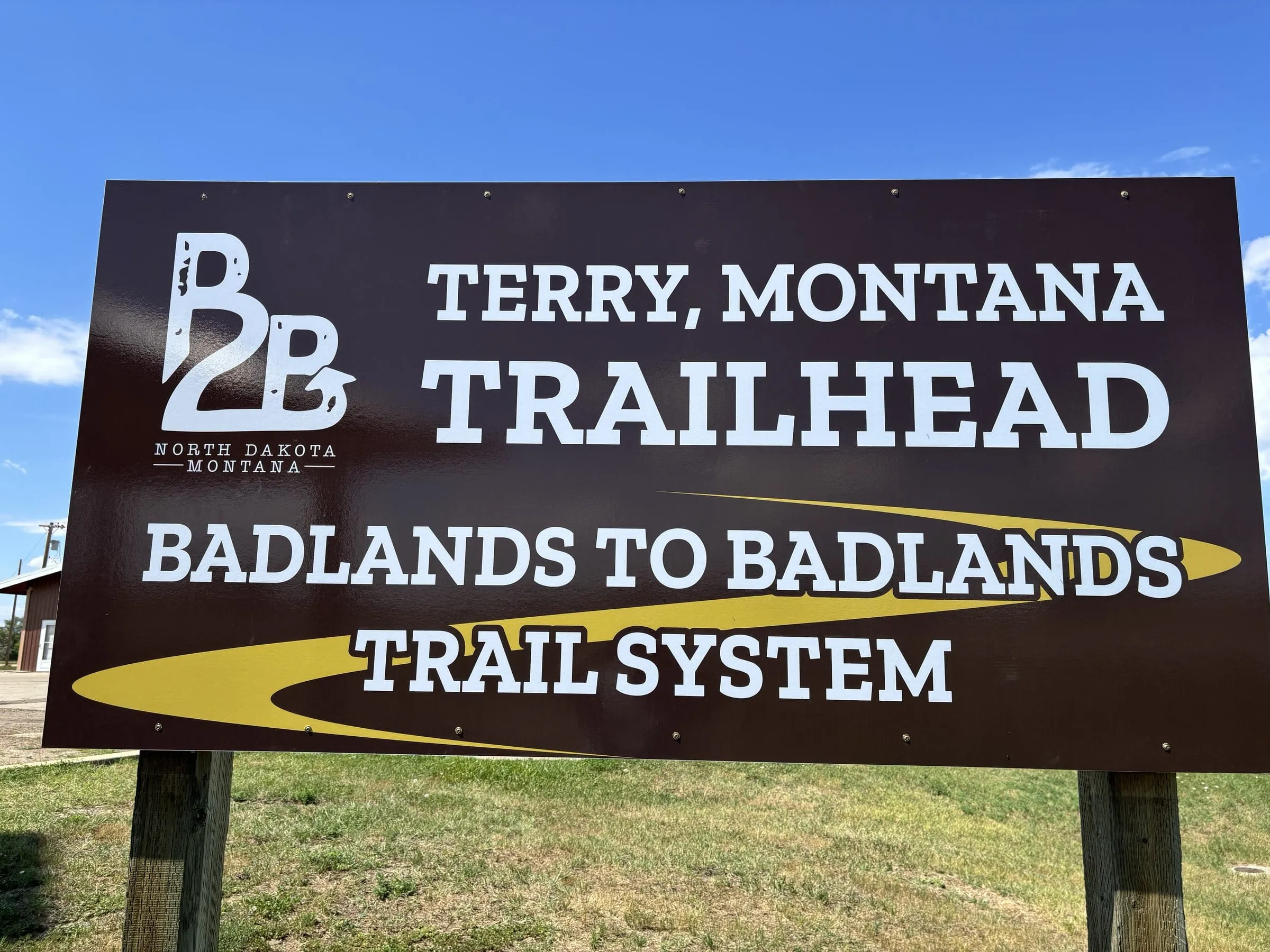 The Badlands to Badlands trailhead sign in Terry, Montana, under a blue sky
